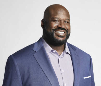 Photo of man wearing blue jacket and light purple button-up shirt smiling at camera