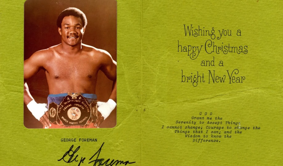 Image of green Christmas card featuring photo of George Foreman in boxing attire with text "Wishing you a Happy Christmas and a Bright New Year"