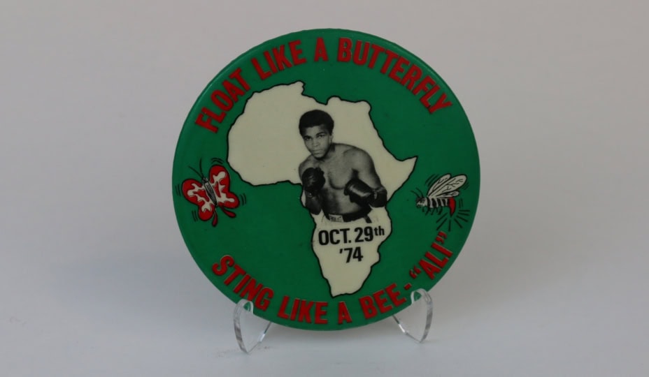 Photo of small circular pin with image of Muhammad Ali and map of Africa behind him