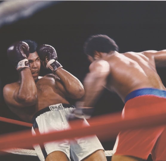 Color photo of Muhammad Ali dodging punch from George Foreman in boxing ring