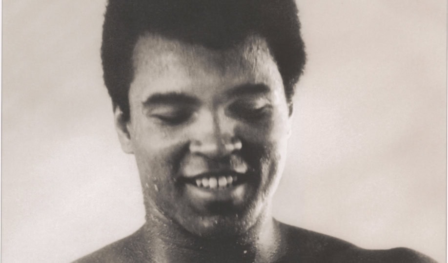 Black and white photo of Muhammad Ali taping up arms and looking down