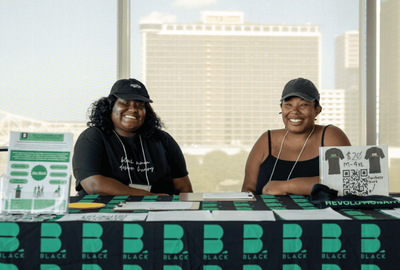 Two women wearing hats sitting at a table and smiling at camera