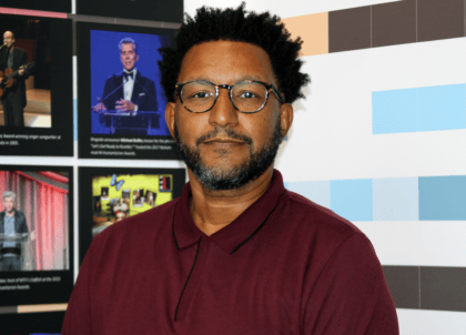 Picture of man wearing glasses and red button-up shirt looking at camera