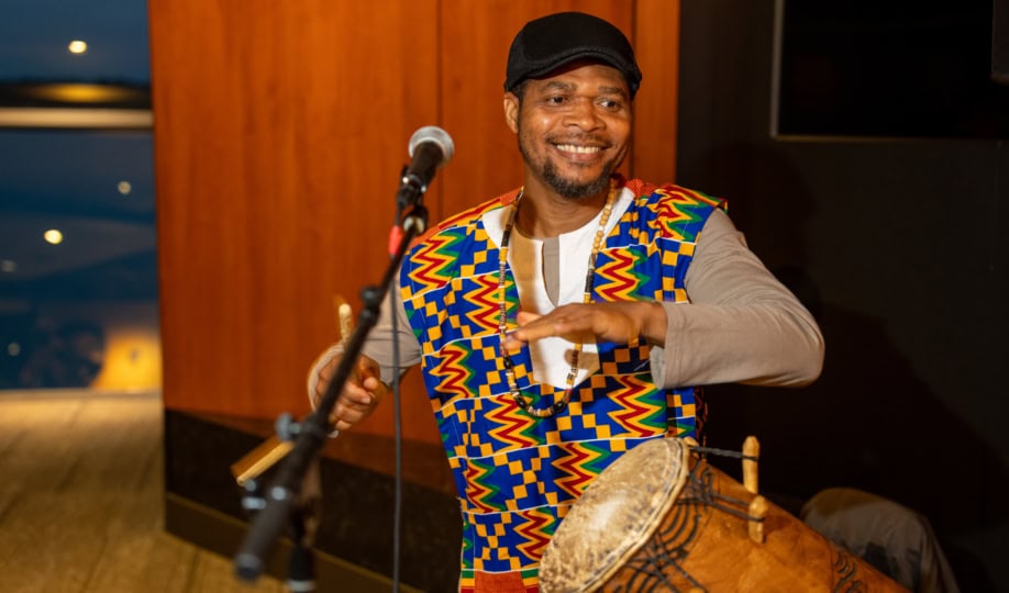 Photo of a man wearing colorful suit playing a drum