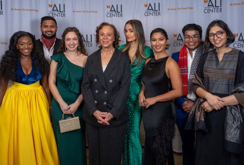 Photo of Lonnie Ali posing with all the Six Core Principle winners in front of Ali Center backdrop