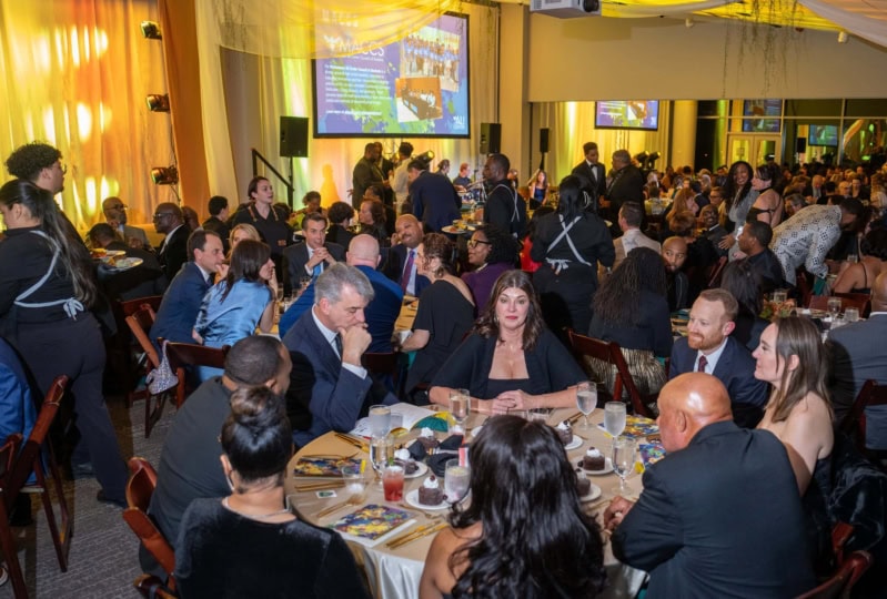 Photo of room with guests gathered around multiple tables