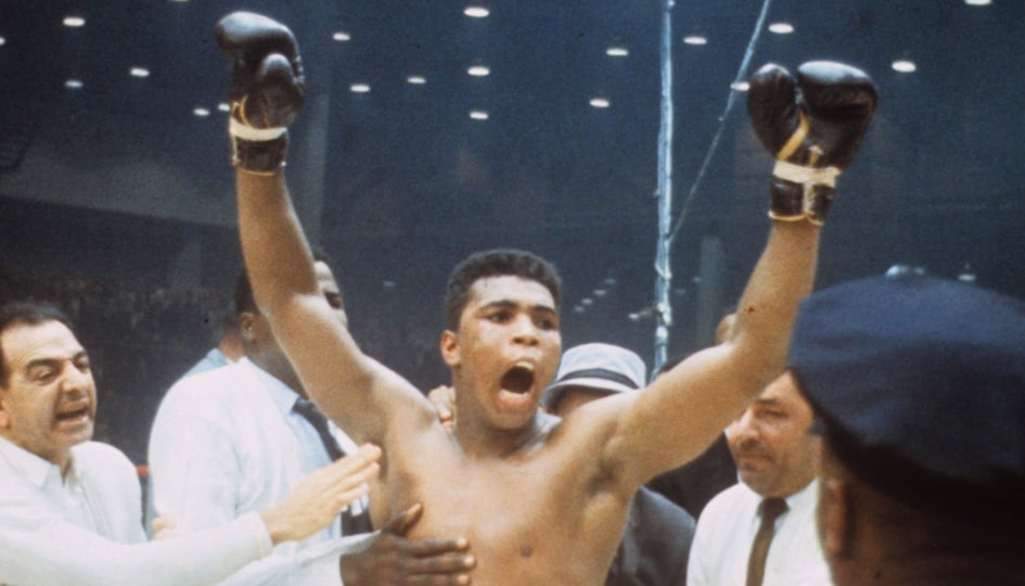 Photo of Muhammad Ali celebrating with gloves in the air