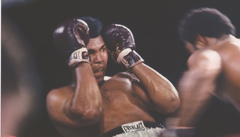 Color photo of Muhammad Ali dodging punch from George Foreman in boxing ring