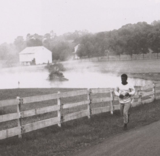 A man runs beside a fence on a long road