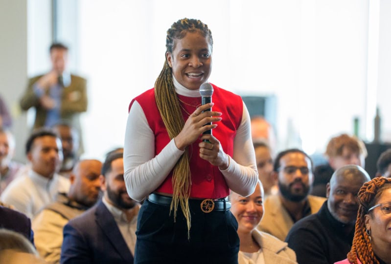 Woman wearing red and white jacket holding microphone with two hands