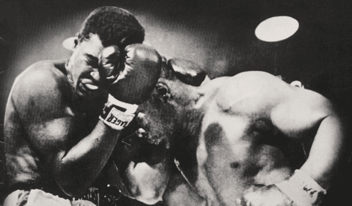 Black and white photo of Muhammad Ali and Sonny Liston grappling with each other in boxing attire