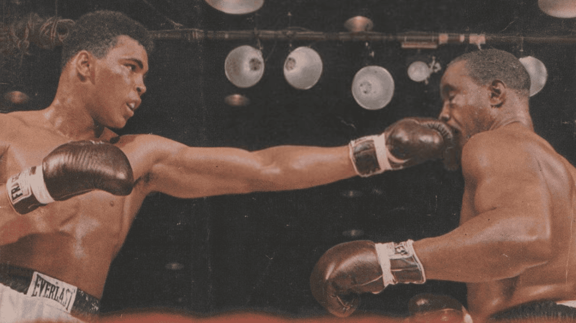 Muhammad Ali and Sonny Liston inside a boxing ring as Liston takes a punch from Ali