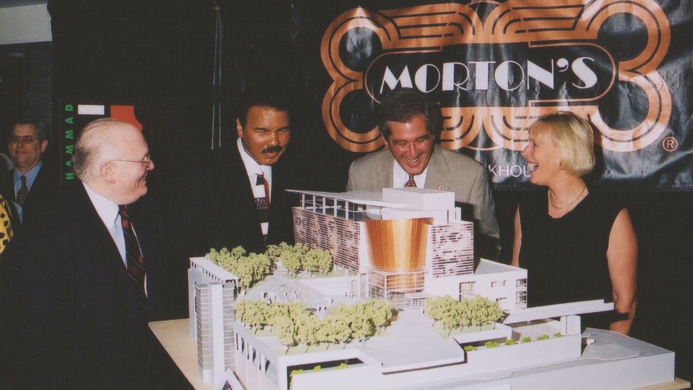 Photo of Muhammad Ali, former mayor Jerry Abramson, and several other guests standing near Ali Center model at event