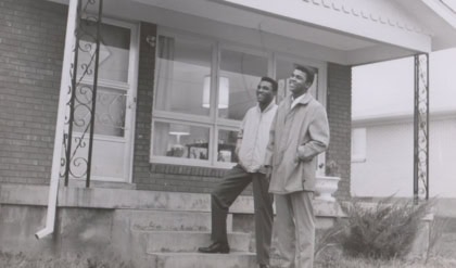 Photo of Rahaman and Muhammad standing outside house on porch steps looking in the sky