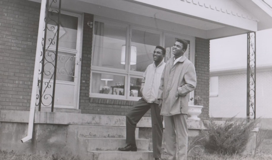 Photo of Rahaman and Muhammad standing outside house on porch steps looking in the sky