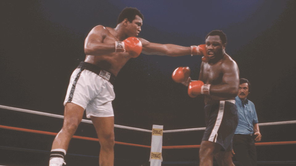 Photo of Muhammad Ali and Joe Frazier within boxing ring as Ali throws punch