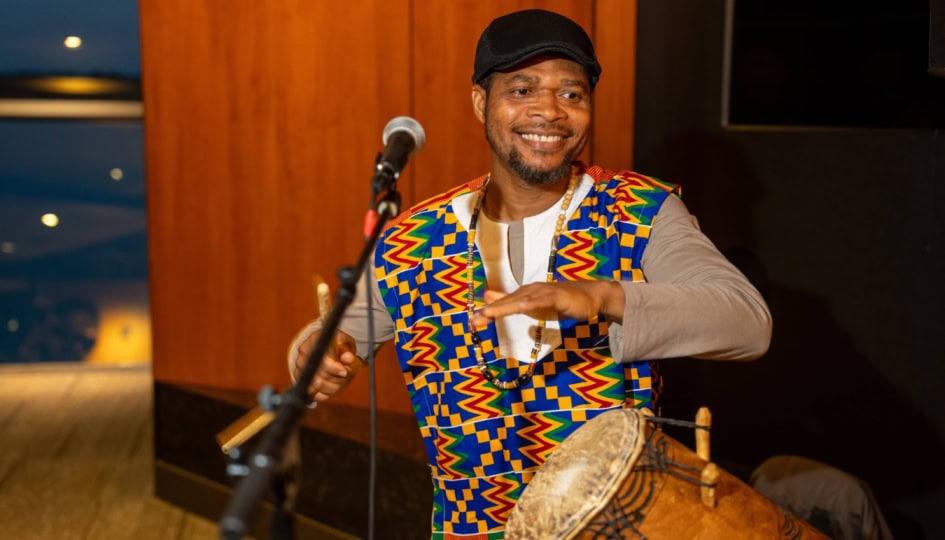 Photo of a man wearing colorful suit playing a drum