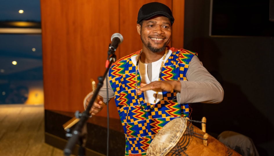 Photo of a man wearing colorful suit playing a drum