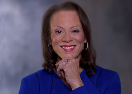 Our Team - Muhammad Ali Center Woman with shoulder length dark hair wearing blue blazer smiling at camera