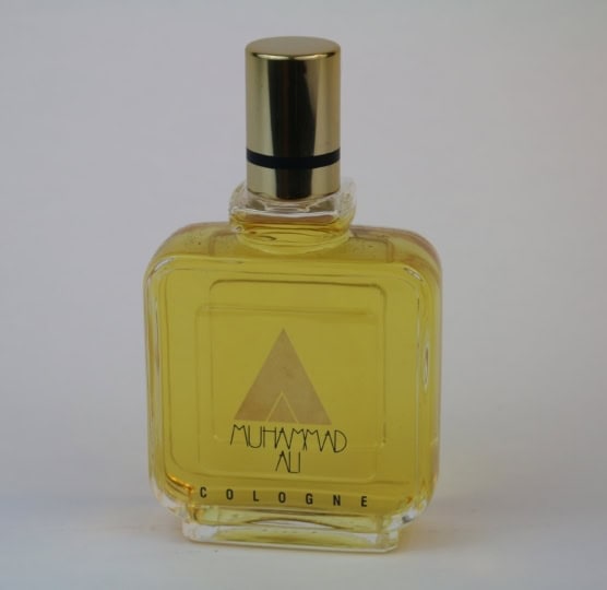 Cologne bottle with yellow liquid and Muhammad Ali branding on bottle
