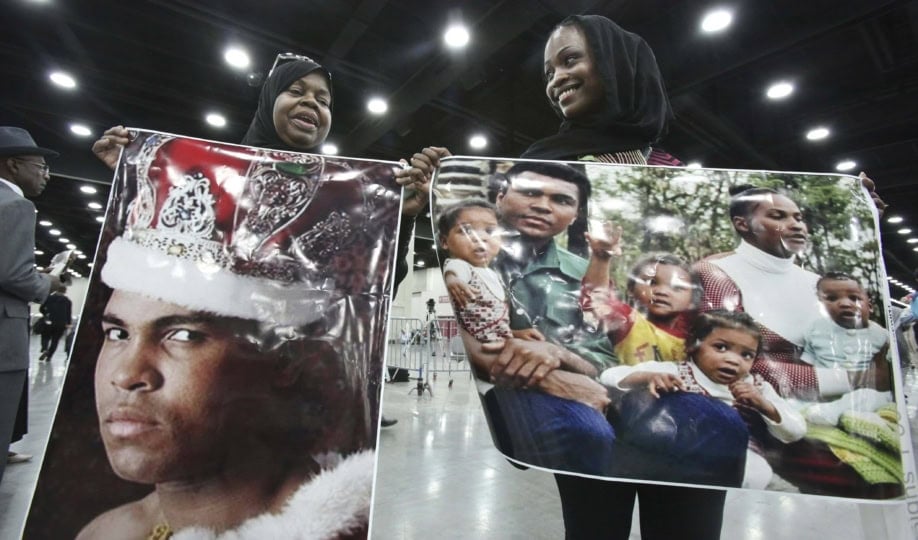 People holding up Muhammad Ali memorabilia inside exhibit space