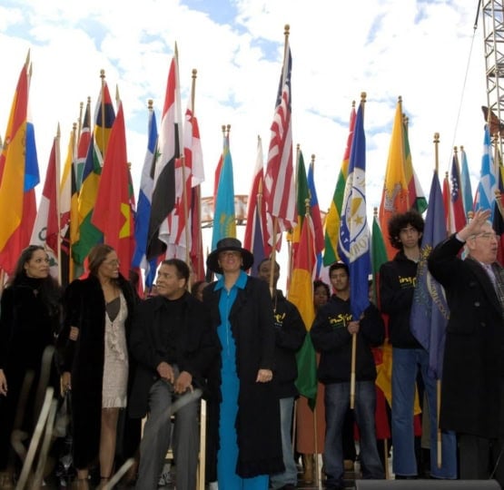 Muhammad, Lonnie and family standing on stage in front of multiple international flags