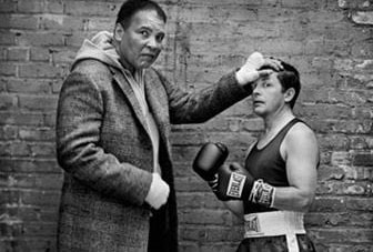 Muhammad Ali holding up head of Michael J. Fox, who is wearing boxing attire