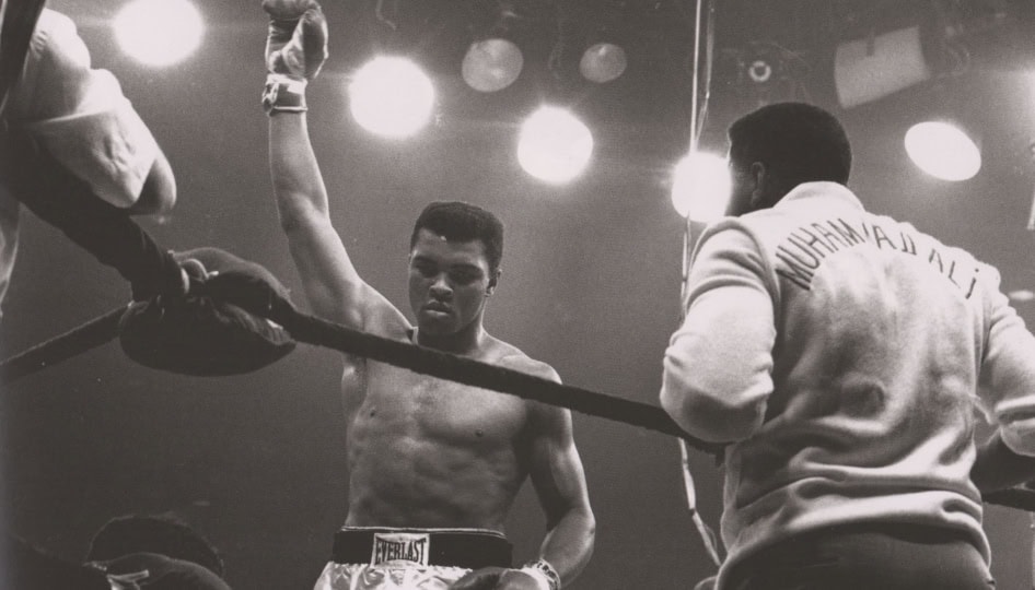 Black and white photo of Muhammad Ali in a boxing ring victorious