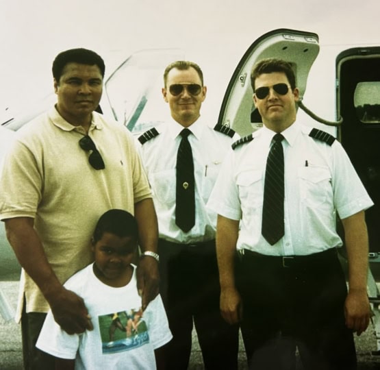 Muhammad Ali and Asaad standing with two pilots in front of plane