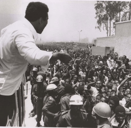 Black and white photo of Muhammad Ali in front of a huge crowd of people in Zaire