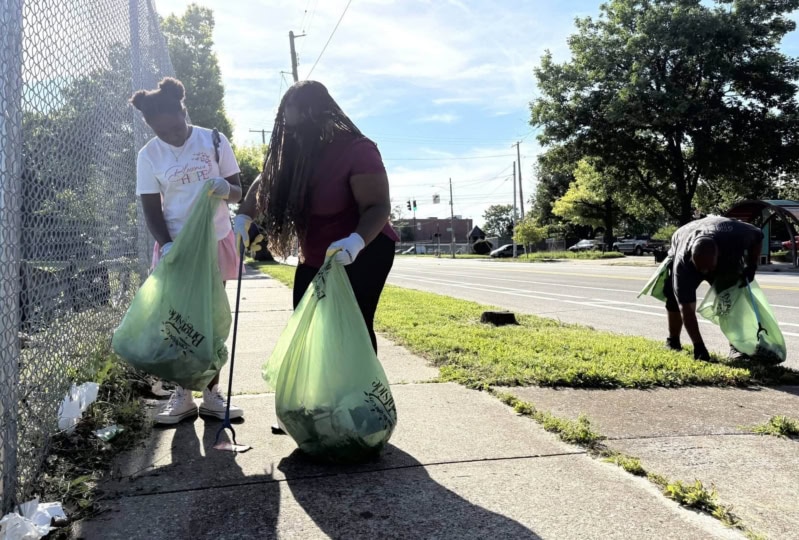 Group of people picking up litter on sidewalk