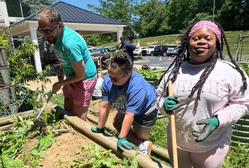 Three people standing near planter bed adding plants