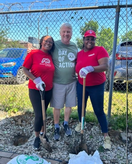 Group of people wearing red and gray T-shirts holding shovels outside