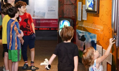 Group of kids and adults viewing a museum exhibit