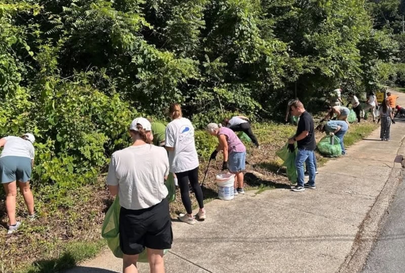 Group of people outside picking up litter near roadway