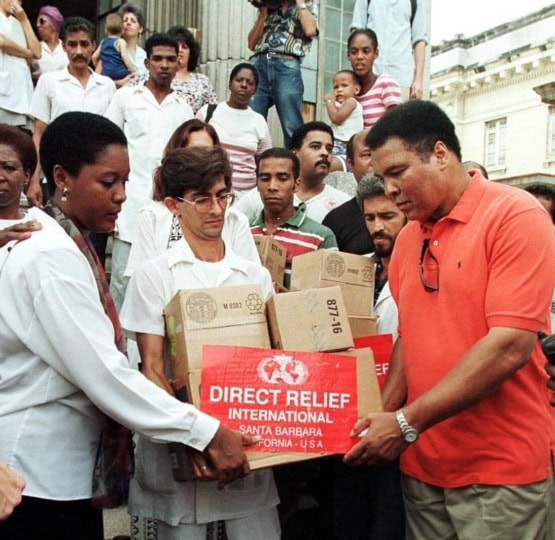 Muhammad Ali standing with group of people offering care packages