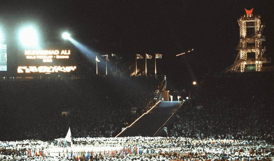 Wide shot of crowd cheering on Muhammad Ali at torch lighting