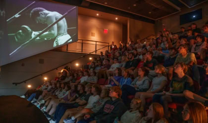 Group of individuals watching a Muhammad Ali film in a theater