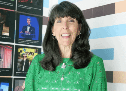 Woman with shoulder-length dark hair wearing green shirt smiling at camera