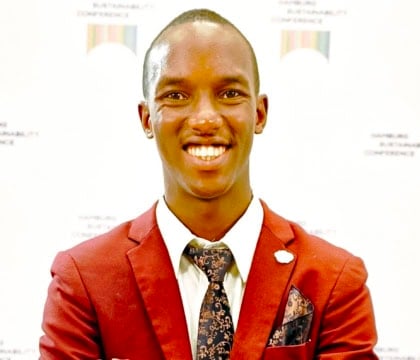 Man wearing red suit and black pants smiling with arms crossed
