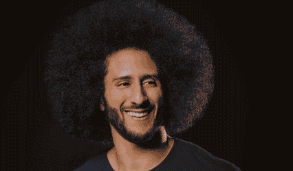 Photo of Colin Kaepernick wearing blue sweater looking off camera and smiling