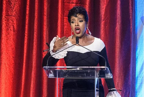 Woman wearing black and white dress singing at podium