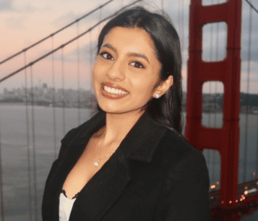 Woman with dark hair wearing black blazer standing near Golden Gate Bridge